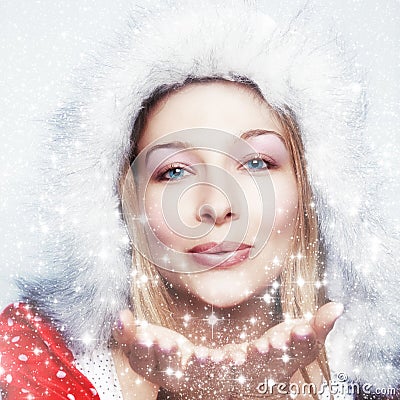 Happy winter woman blowing snowflakes