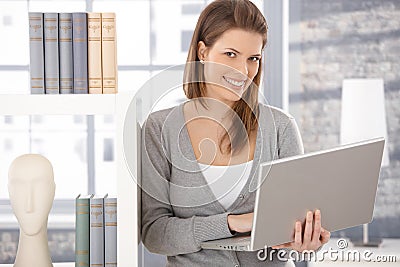 Happy woman at bookcase with computer