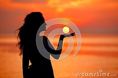 Happy Woman enjoying in Sea Sunset. Silhouetted against the suns