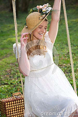 Happy woman with hat sitting on a swing outdoors