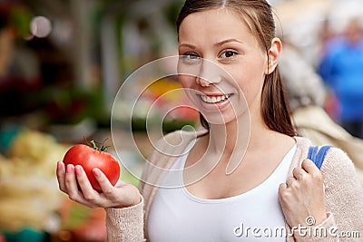 Happy woman holding tomato at street market