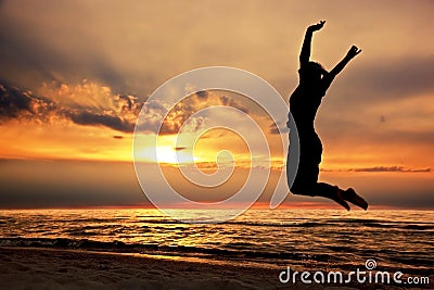 Happy woman jumping on the beach at sunset