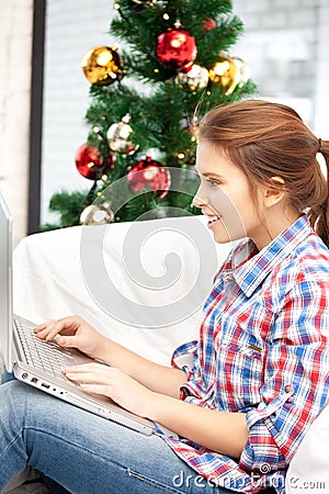 Happy woman with laptop and christmas tree