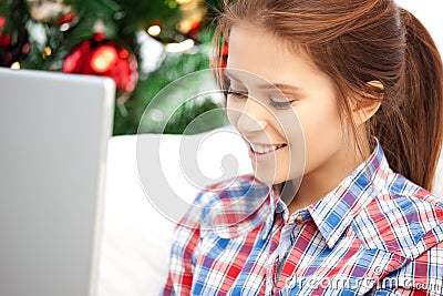 Happy woman with laptop and christmas tree