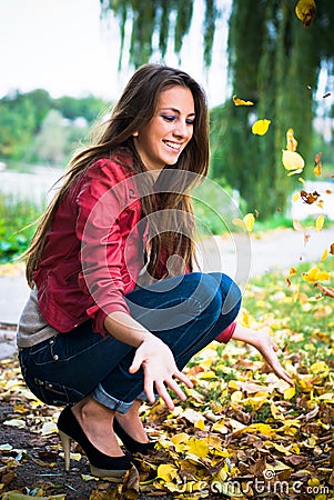 Happy woman playing with yellow leaves