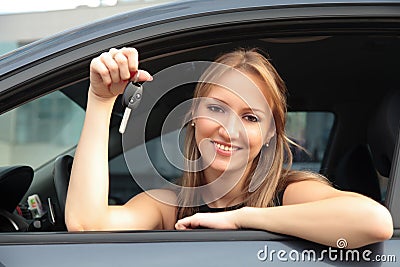 Happy woman showing key of a new car