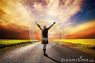 Happy woman standing on long road at sunset