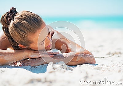 Happy woman in swimsuit relaxing while laying on beach