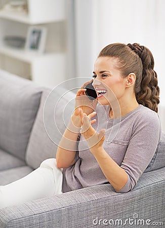Happy woman talking phone in living room