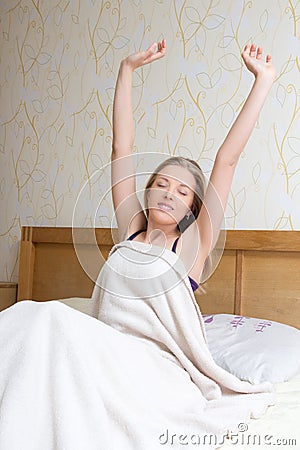 Happy woman waking up and stretching her arms up