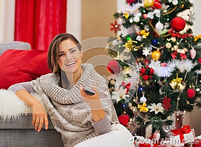 Happy woman watching TV near Christmas tree