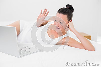 Happy woman waving hand at laptop screen