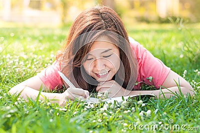 Happy Young Asian Woman Writing in Notebook and Smiling