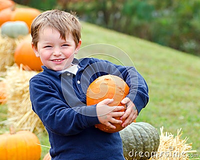 Happy young boy picking a pumpkin