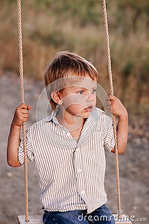 Happy young boy playing on swing in a park