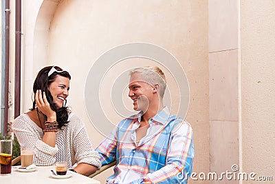 Happy young couple sitting outside cafe restaurant drinking coffee