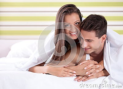 Happy young couple under covers in bed