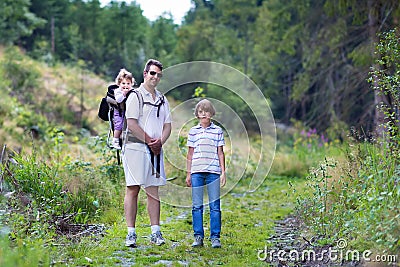 Happy young family hiking in beautiful autumn forest