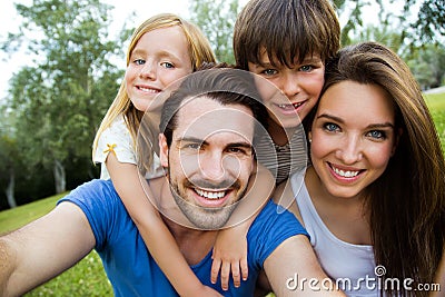 Happy young family taking selfies with her smartphone in the par