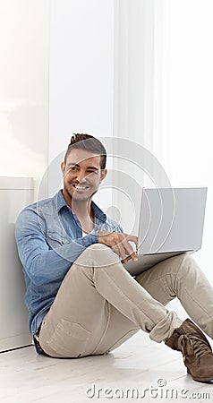 Happy young man browsing internet at home