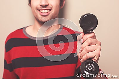 Happy young man holding telephone