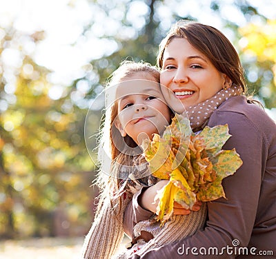 Happy young mother with daughter in autumn park