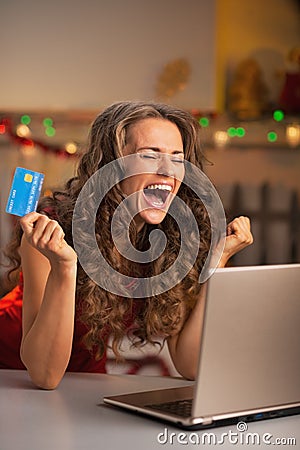 Happy young woman with credit card and laptop rejoicing