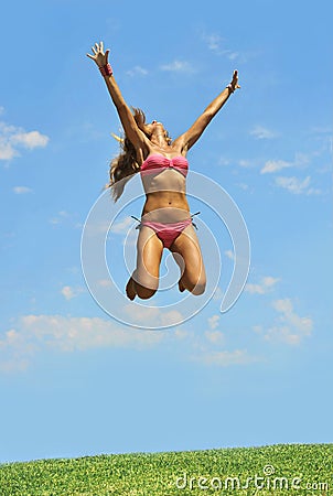 Happy young woman jumping to the air in summer sky
