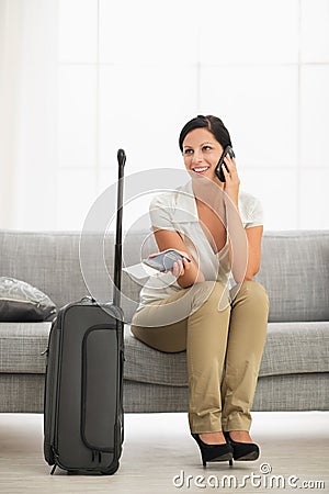 Happy young woman in living room with travel bag