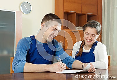 Happy young workers in uniform with financial documents at tabl