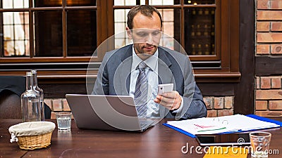Hard working businessman in restaurant with laptop and mobile phone.