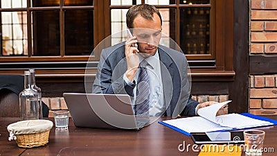 Hard working businessman in restaurant with laptop and mobile phone.