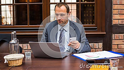 Hard working businessman in restaurant with laptop and mobile phone.