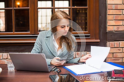 Hard working businesswoman in restaurant with laptop and mobile phone.