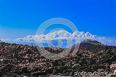 Hardened lava of the volcano on the background of blue sky.