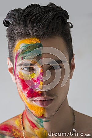 Head-shot of attractive young man, skin painted with Holi colors