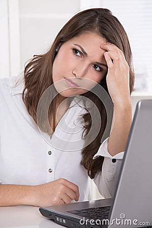 Headache: businesswoman scratching forehead with laptop