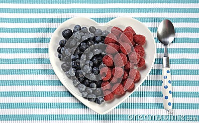 Healthy diet high dietary fiber breakfast with blueberries and raspberries in heart plate