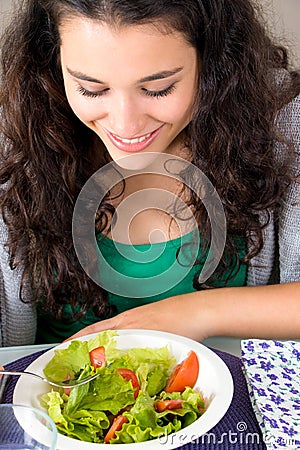 Healthy and happy young woman eating salad