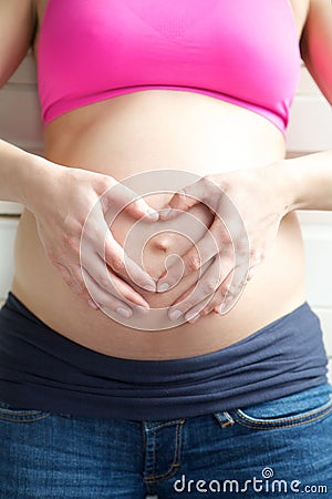 Heart shape with hands in front of pregnant stomach