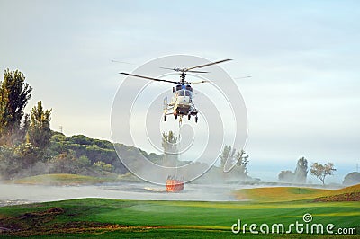 Helicopter collecting water for fire fighting, Spain.
