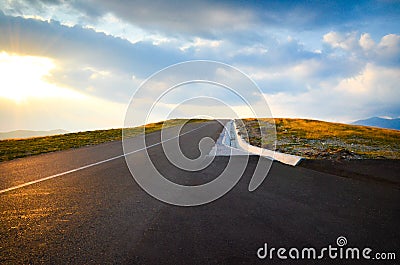 A highway over the mountains at sunset with a blue cloudy sky