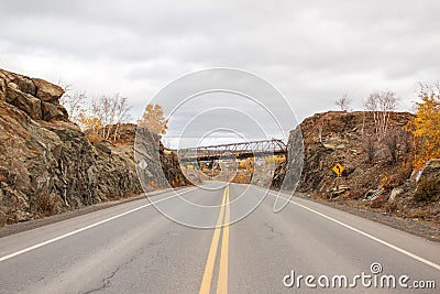 A highway between a rock ridge with a bridge overhead