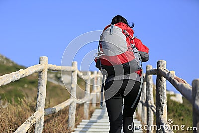 Hiking woman climbing up to mountain peak