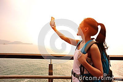 Hiking woman taking photo seaside