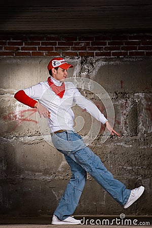 Hip hop boy dancing in modern style over grey wall