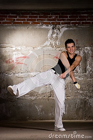 Hip hop boy dancing in modern style over grey wall