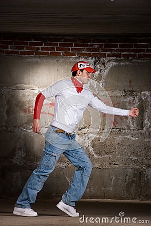 Hip hop boy dancing in modern style over grey wall
