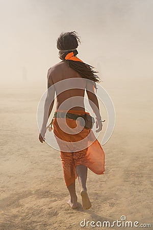 Hippie man walking in a sand storm dressed with orange fabrics