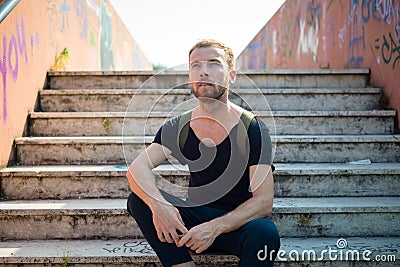 Hipster modern stylish blonde man sitting in stairs